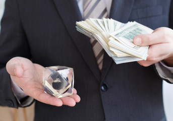Businessman in suit, tie holds in hands drop of black oil of Brent brand in crystal cube.Pack of...