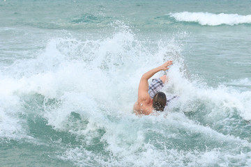 young man on a surfing board crashes on the beach 