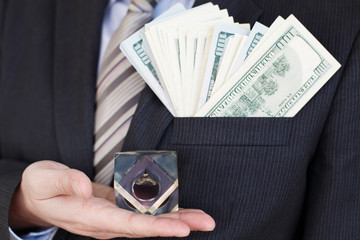 Businessman in suit, tie holds in hands drop of black oil of Brent brand in crystal cube.Pack of...