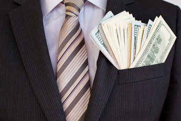 Pack of hundred dollars bills in pocket of suit of businessman in shirt and tie. Successful...