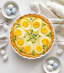 Vegetarian tart quiche with eggs and green peas in casserole dish view from above