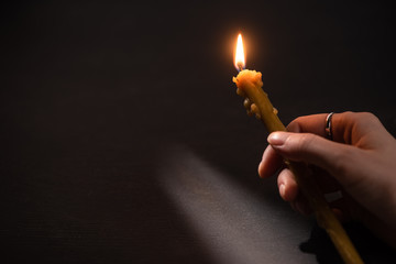 cropped view of woman holding burning church candle in dark