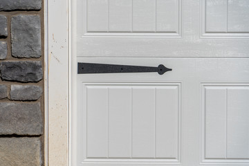 Black powder coated steel spade strap hinge pointing to left on a raised panel white garage door...