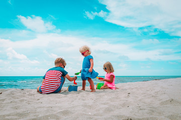 kids- boy and girls- play with sand on beach