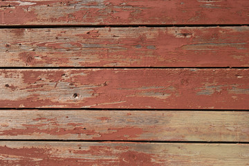 Wall of old boards with cracked red paint. Creative vintage background. Pine boards are red.