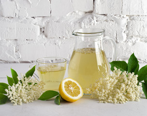 Refreshing drink and elderberry flowers in decanter and glass