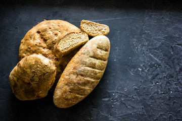  Whole grain bread. Fresh homemade bread. French sourdough bread. Loaves of various bread on a dark background, top view, copy space