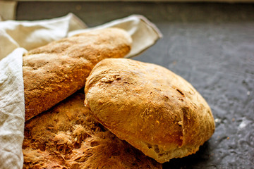 Assorted homemade bread close-up. Several loaves of bread on a dark table. The concept of home baking and bread production. Background about bread