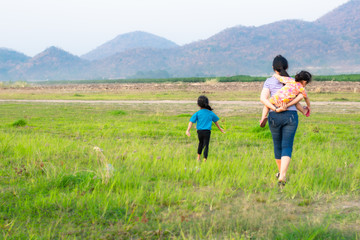 Fototapeta premium Mother and two children standing in the meadow