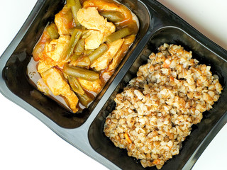 Proper food, buckwheat and chicken with string beans, in a plastic container. Food delivery.