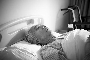 sick old man lying in hospital bed alone