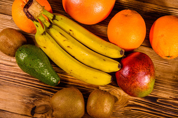 Still life with exotic fruits. Bananas, mango, oranges, avocado, grapefruit and kiwi fruits on wooden table. Top view