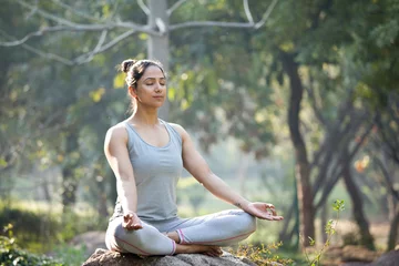 Foto op Plexiglas Woman practicing yoga in lotus position at park © creativeimages
