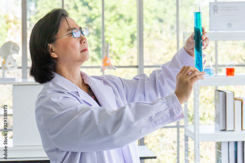 Aufkleber discovering a cure for an asian female scientist who is concentrated, holding a test tube and watchi