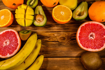 Still life with exotic fruits. Bananas, mango, oranges, avocado, grapefruit and kiwi fruits on wooden table. Top view