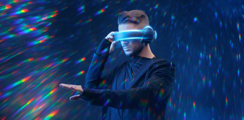 Guy using VR helmet scrolling invisible screen while interacting with virtual reality. Blue neon light. Augmented reality, future technology, game concept. © KDdesignphoto