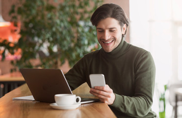 Wealthy young businessman using phone while working at cafe