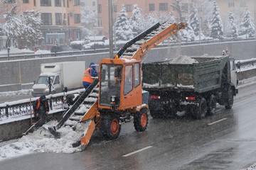 Snow removing equipement in the street in blizzard. Tractor cleaning the road from the snow....