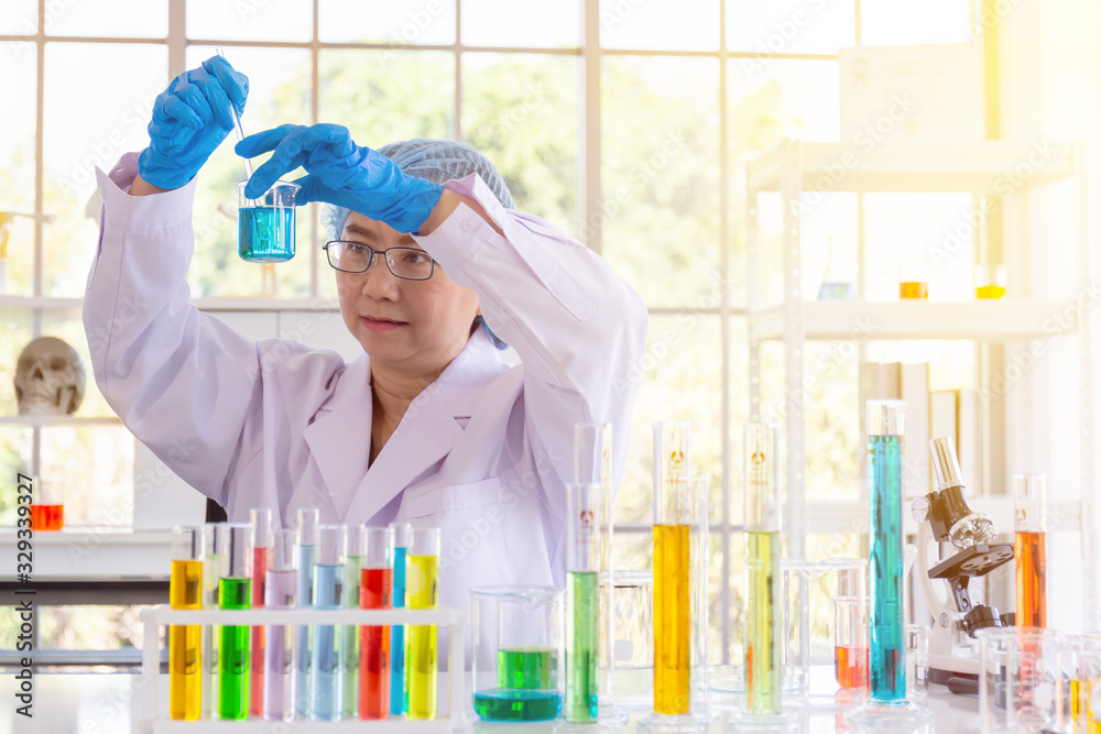 Aufkleber discovering a cure for an asian female scientist who is concentrated, holding a test tube and watchi