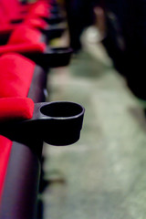 Fototapeta na wymiar Cup holder The emptiness of the red seat in the cinema View from the side Prepared to support customers in watching movies The cushion is made of felt.