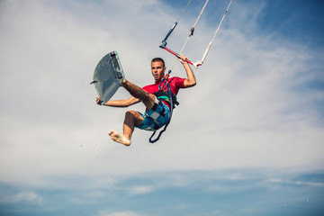 Professional kiter makes the difficult trick on a beautiful background. Kitesurfing Kiteboarding action photos man among waves quickly goes