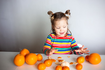 Little girl, 3 year old baby, with a ponytail hairstyle in a colorful colorful striped jacket with a huge number of appelsins and tangerines