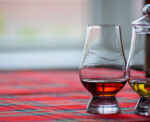 Special tulip-shaped glass for tasting of Scotch whisky on distillery in Scotland, UK and red tartan