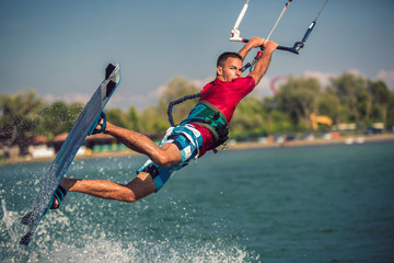 Professional kiter makes the difficult trick on a river. Kitesurfing Kiteboarding action photos man...