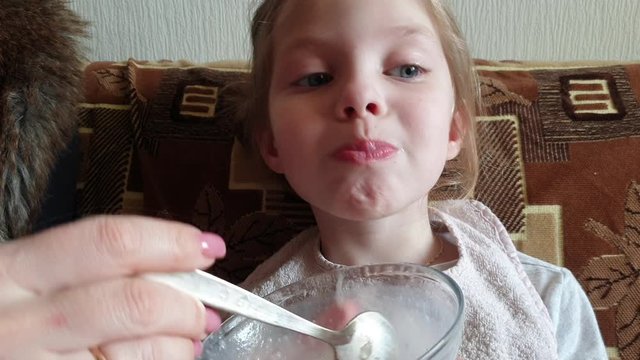 a woman feeds a little girl oatmeal for dinner in the kitchen