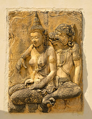 old mural sculpture on stone wall of ancient Buddhist temple. figure of women and Asian deity from stone