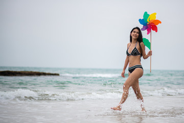 Woman Holding Pinwheel Toy While Walking At Beach Against Sky