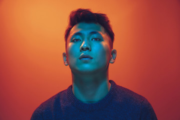 Portrait of a guy with colorful neon light on gradient studio background. Male model with calm and serious mood. Facial expression, cyberpunk, millenials lifestyle and look like. Future, technologies.