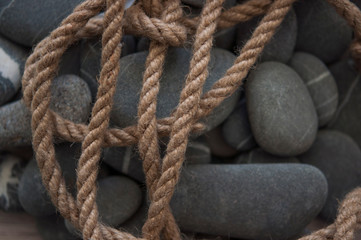 Fototapeta premium many gray pebbles with hemp rope background, space for text.