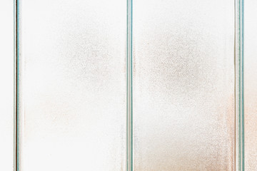 Old frosted patterned glass on a tiled window. Texture, transparent, matte white and grey frosted glass, blur effect. Stained glass decorative background © Ivan