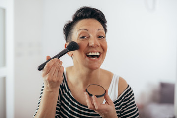 mid aged woman holding makeup brushes