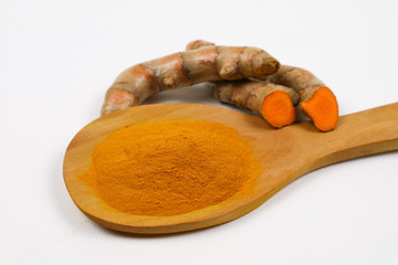 Turmeric powder in a wooden spoon and fresh turmeric roots isolated on a white background is an ingredient in turmeric foods and ingredients in skin care products. Turmeric helps strengthen the skin.
