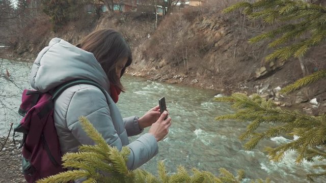 Female traveler taking photos with her smartphone. Girl travel blogger filming nature. Women backpacker walking outdoor. Self isolating at the nature. 