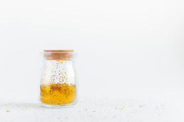 Gllitter bokeh background. Golden color glitter and confetty in  a glass bottle. Main trend concept. Natural and authentic mood.