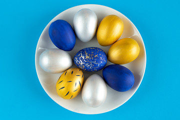 Christ is risen. Plate with Easter eggs in silver, gold and blue.