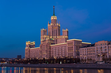 View of illuminated Stalin skyscraper on the Kotelnicheskaya embankment and Moscow River at night