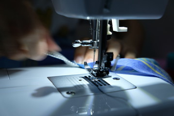A tailor is sewing clothes with a sewing machine. - obrazy, fototapety, plakaty