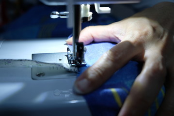 A tailor is sewing clothes with a sewing machine.