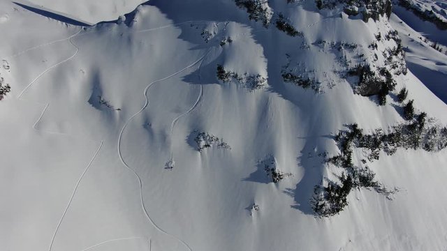 High tracking aerial of snowboarder freeriding off-piste on huge mountain
