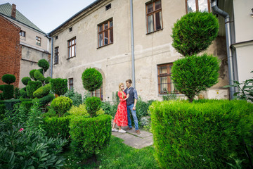 Obraz premium a young couple is stylishly dressed, a girl in a red dress, a man in a blue shirt and blue pants, walk the streets in Italy