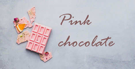 Chocolate pink whole bar decorated with slices of fruits nuts and slices gray text Chocolate background. Minimization