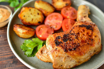 Fried chicken legs in a plate with vegetables. Tasty lunch or dinner. Barbecue, grilled meat. Chicken thighs and drumsticks.