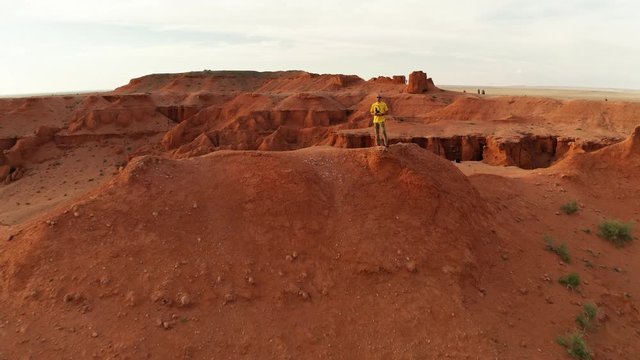 Aerial view of a man in a canyon in the Gobi Desert at sunset. Mongolia, Gobi, Bayanzag valley, Flaming Cliffs. Drone footage
