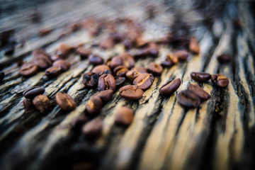  The coffee beans spilled on a wooden table with natural stripes.