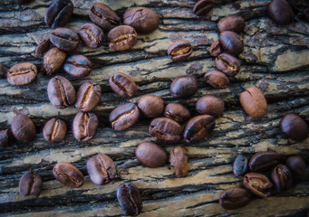  The coffee beans spilled on a wooden table with natural stripes.