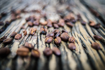  The coffee beans spilled on a wooden table with natural stripes.